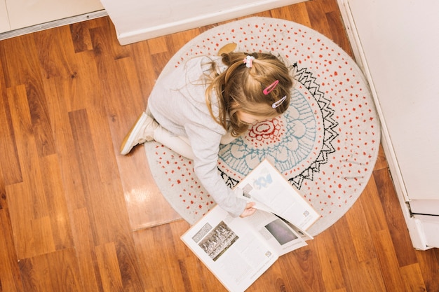 Free photo anonymous girl reading book on floor