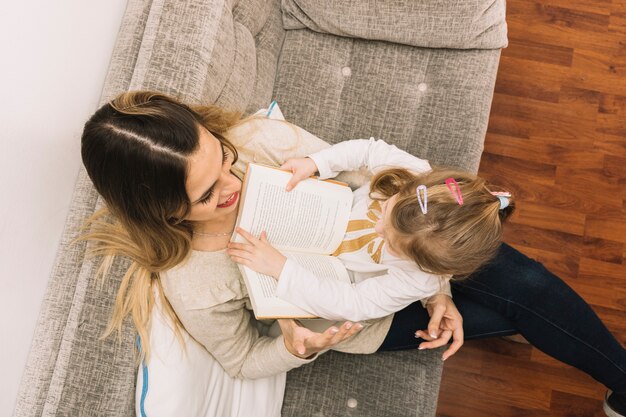 Anonymous girl reading book to mother