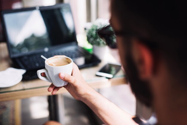 Anonymous man having fresh coffee in cafe