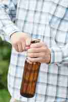 Free photo anonymous man opening beer in nature