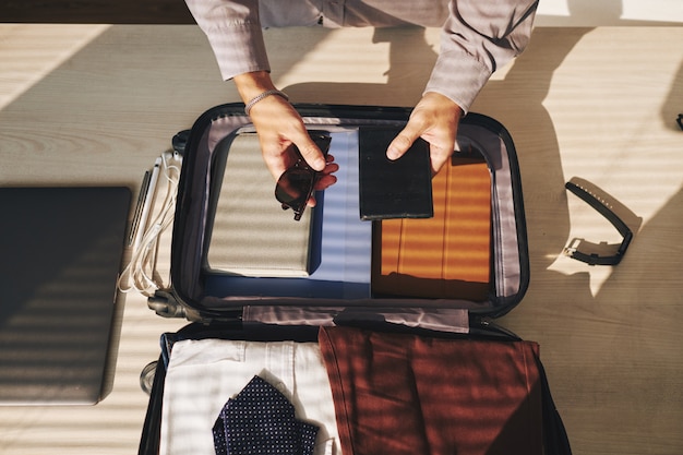 Анонимный мужчина упаковывает чемодан для путешествий