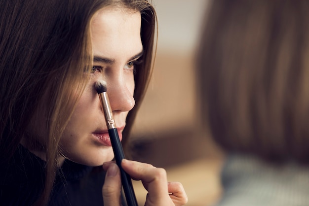 Anonymous stylist applying highlighter on model