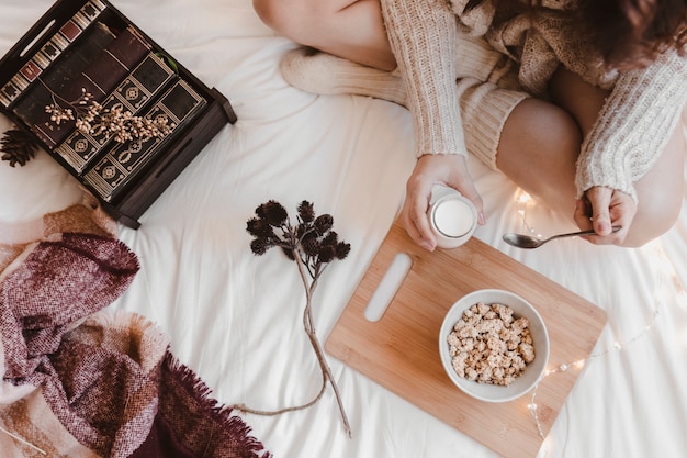 Anonymous woman eating yogurt on bed