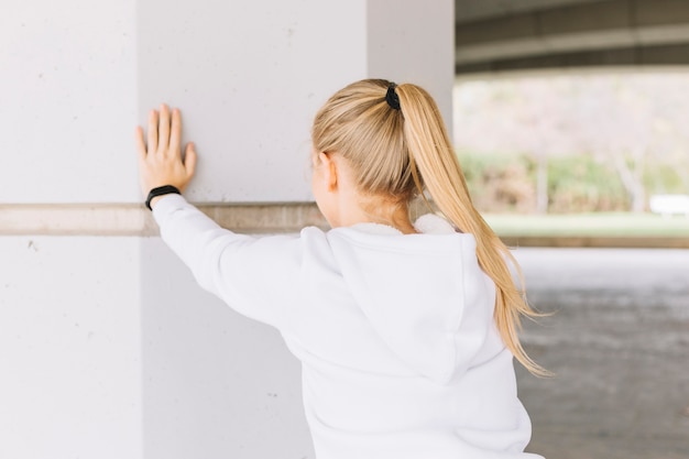 Free photo anonymous woman exercising near pillar