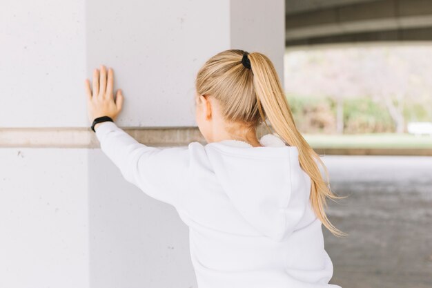 Anonymous woman exercising near pillar