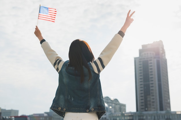 Anonymous woman raising hands and American flag in honor of Independence Day