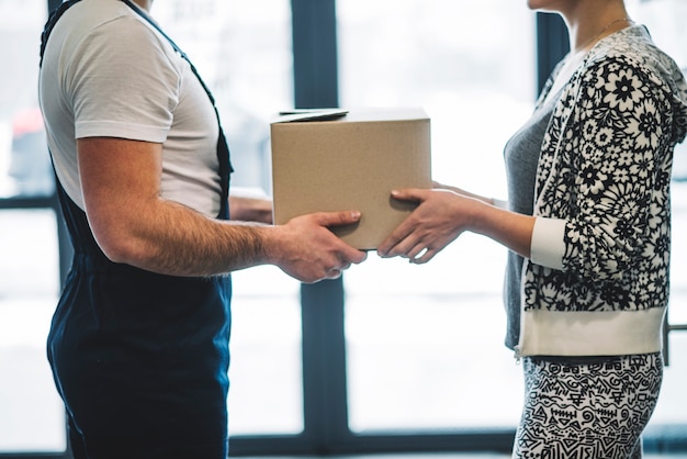 Free photo anonymous woman receiving parcel with courier