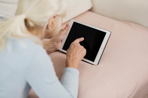 Anonymous woman resting on sofa with tablet