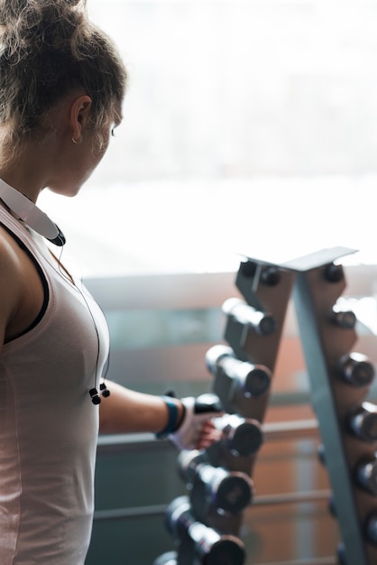 Donna anonima che prende dumbbell dalla cremagliera