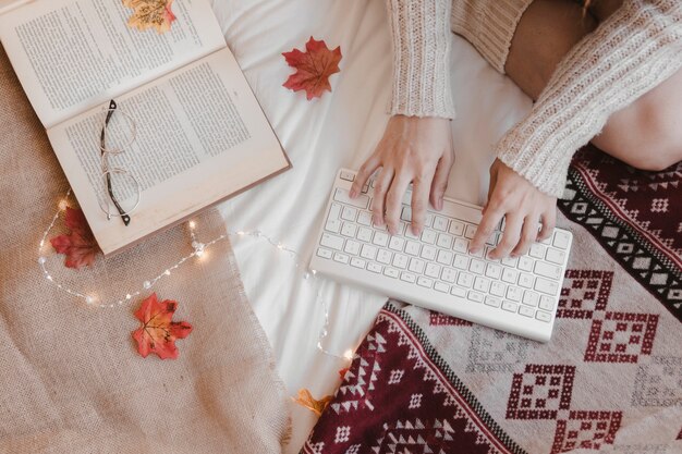 Anonymous woman using keyboard near book