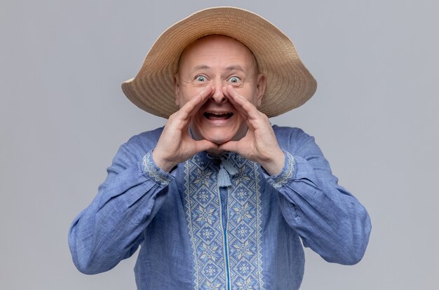 Anxious adult slavic man with straw hat and in blue shirt keeping hands close to his mouth and 