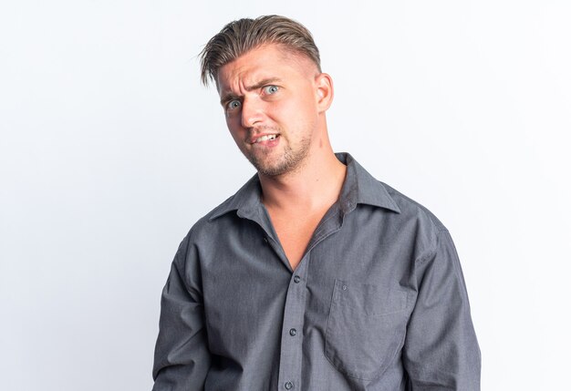 Anxious blonde handsome man  isolated on white wall with copy space