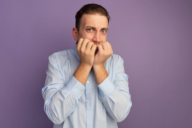 Anxious handsome blonde man bites nails isolated