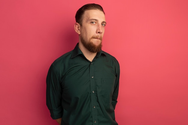 Anxious handsome blonde man looks at front isolated on pink wall