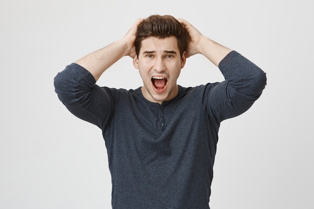Free photo anxious panicking handsome man shouting alarmed, grab head