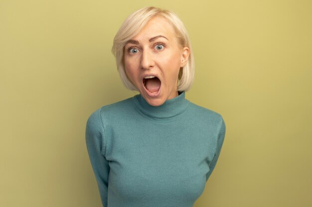 Anxious pretty blonde slavic woman looks at front isolated on olive green wall