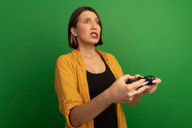 Обеспокоенная симпатичная кавказская женщина держит игровой контроллер и смотрит на изолированную сторону