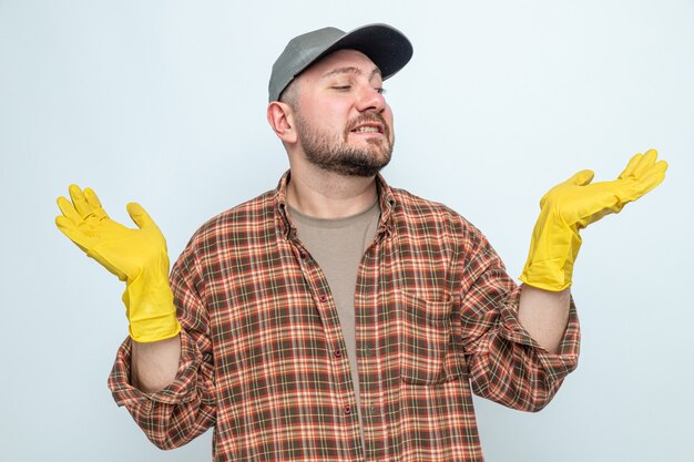 Anxious slavic cleaner man with rubber gloves keeping hands open and looking at side 