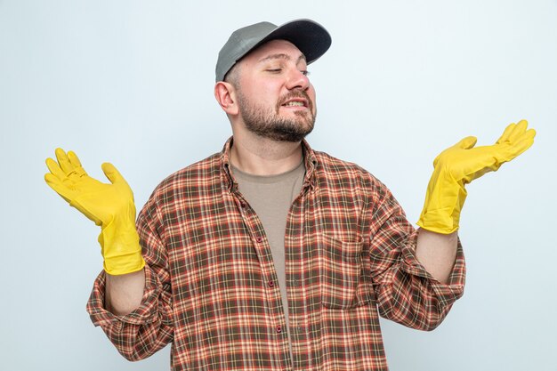 Тревожный славянский уборщик в резиновых перчатках держит руки открытыми и смотрит в сторону