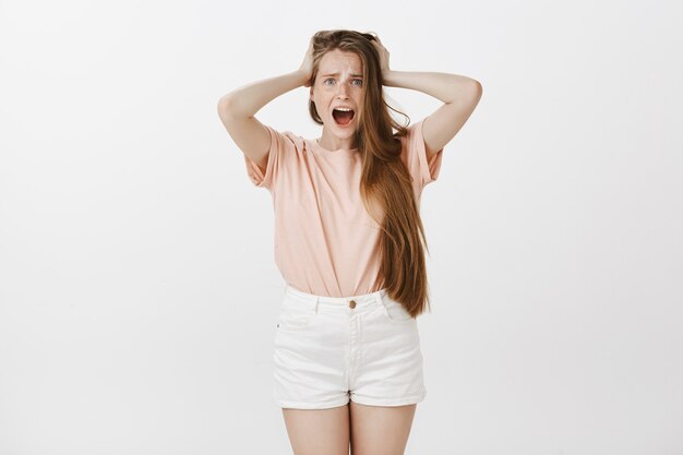 Anxious teenage girl posing against the white wall