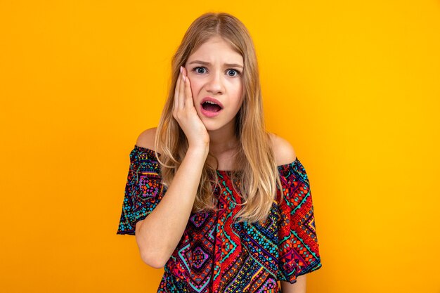 Anxious young blonde slavic woman putting hand on her face and looking 