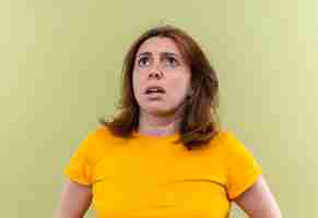 Free photo anxious young casual woman looking up on isolated green space