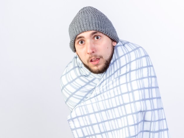 Anxious young caucasian ill man wearing winter hat wrapped in plate 