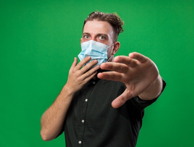 Anxious young ill slavic man wearing medical mask stretching out hand 