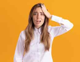 Free photo anxious young pretty caucasian girl puts hand on forehead and looks at camera on orange