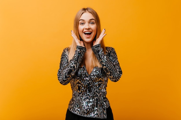 Appealing woman in party jacket smiling on orange. Debinair female model expressing happiness.