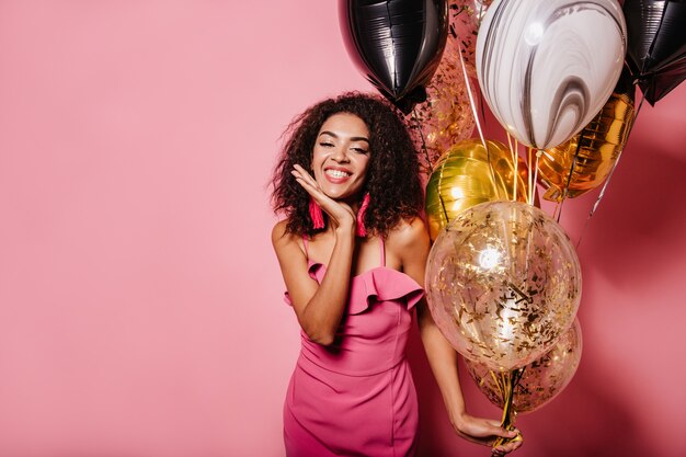 Appealing woman posing on pink wall with smile