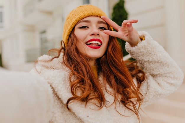 Attraente donna con i capelli allo zenzero in posa nella fredda giornata invernale. foto all'aperto di una bella ragazza dai capelli rossi.