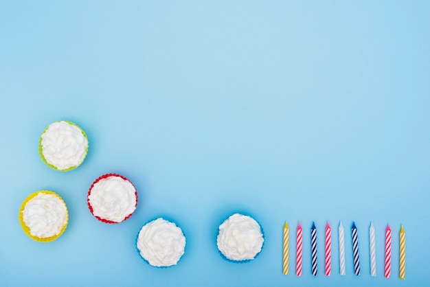 Appetizing cakes and candles on blue background