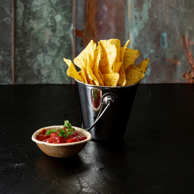 Appetizing corn chips and salsa sauce on table