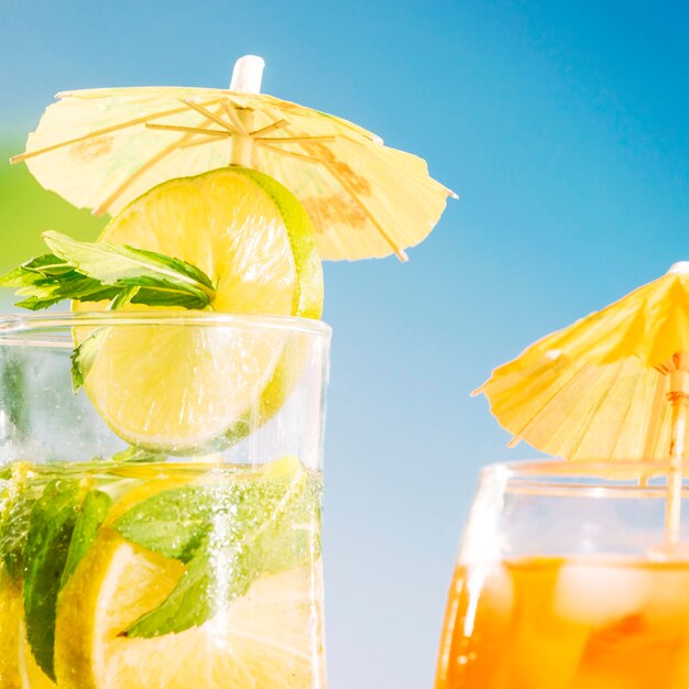 Appetizing drink with sliced lime and mint sprigs  in umbrella decorated glass