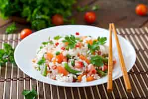 Free photo appetizing healthy rice with vegetables in white plate on a wooden table.