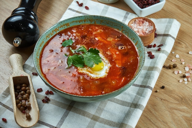Аппетитный красный суп на мясном бульоне с овощами и перепелиным яйцом. крупным планом зрения. вкусная еда