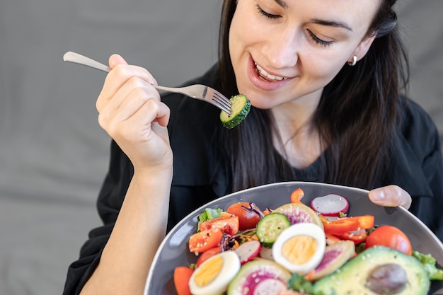 女性の手で皿に新鮮な野菜と卵の食欲をそそるサラダ