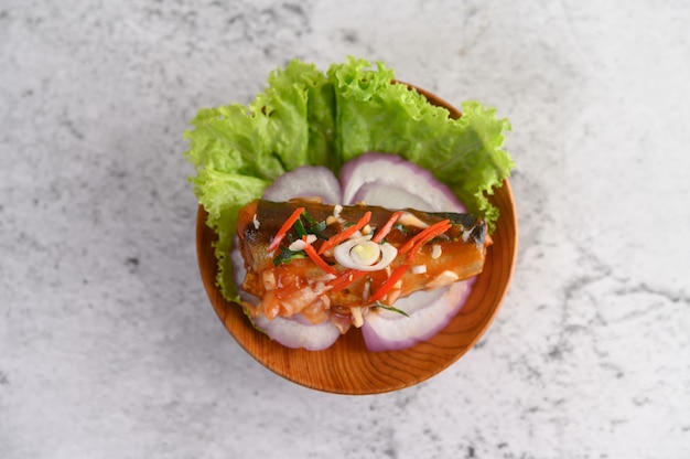 Appetizing spicy canned sardine salad with spicy sauce in wood bowl