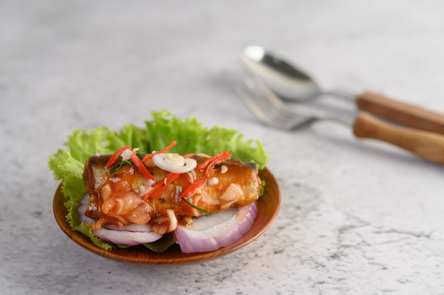 Appetizing spicy canned sardine salad with spicy sauce in wood bowl