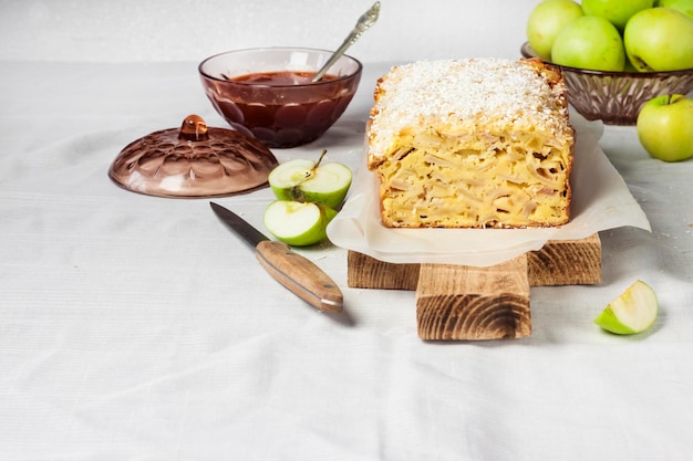 木製のまな板にリンゴとココナッツのオークケーキ、花瓶にリンゴ。コピースペース