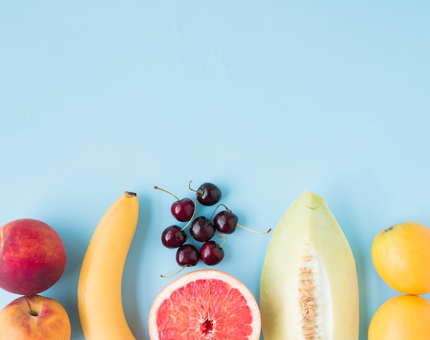 Mela; banana; ciliegie; pompelmo; melone e limoni su sfondo blu