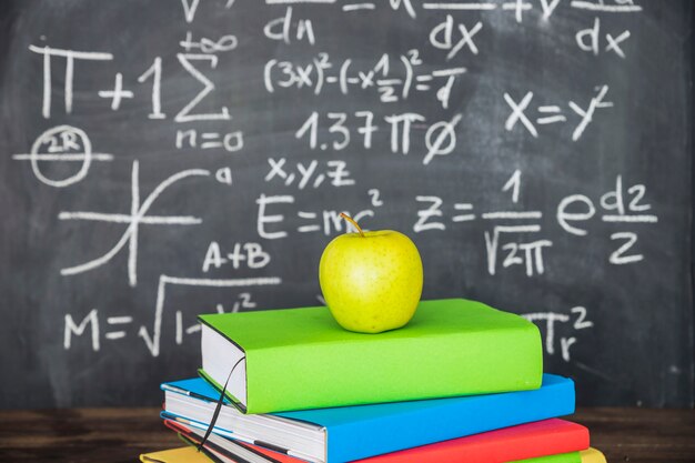 Apple on books pile near chalkboard