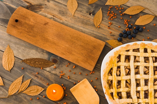 Apple cake near cutting board between foliage