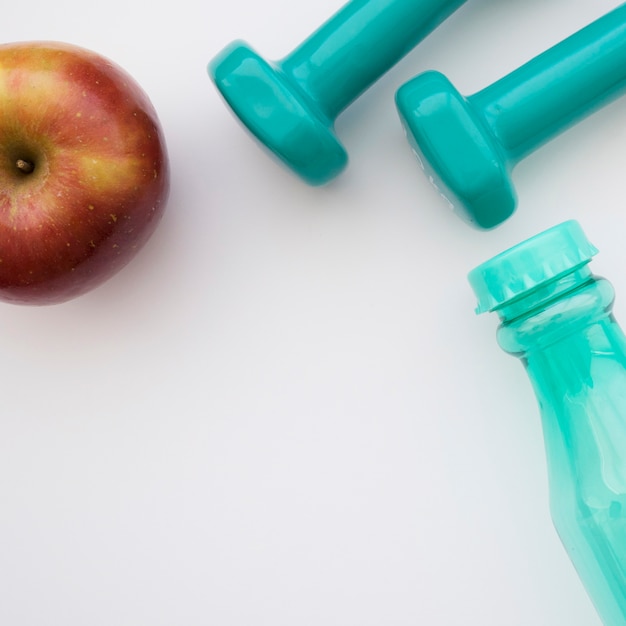 Apple, dumbbells and bottle close up