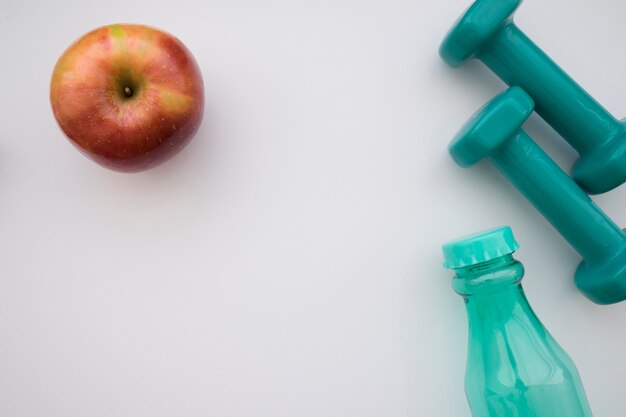 Apple, dumbbells and bottle