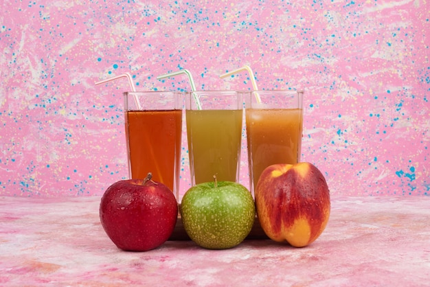 Free photo apple and peaches with colorful glasses of juice.