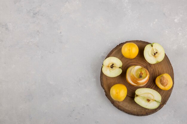 Apple, pear and peaches on a piece of wood, top view