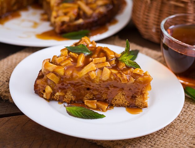 Apple pie with caramel sauce on a wooden background