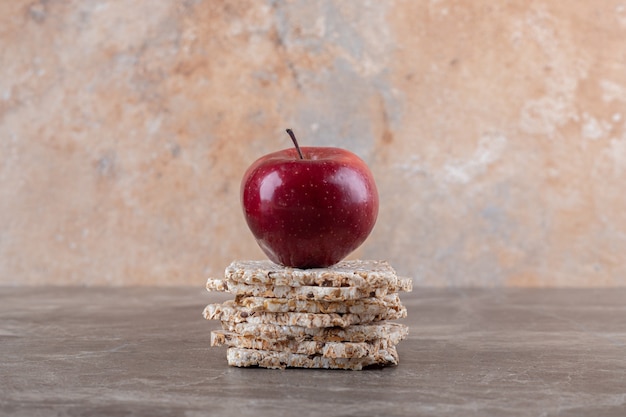 Apple and a pile of puffed rice cakes on the marble surface